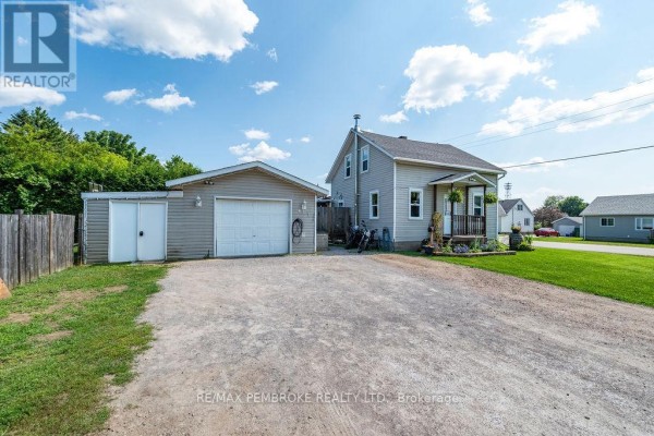 View of the house and garage from the driveway, showing the gravel surface and well-maintained lawn. - 617 Third Avenue S, Laurentian Valley