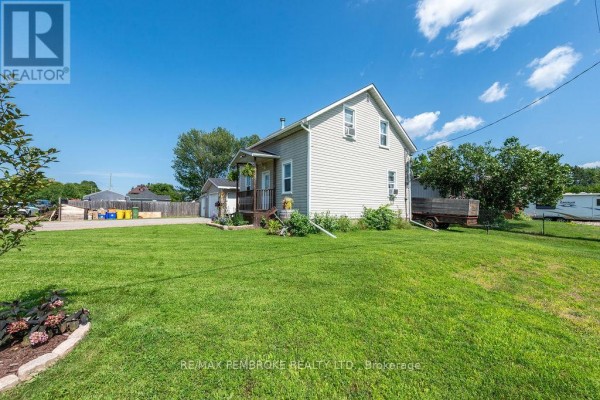 Rear exterior view of the house and garage, with a large grassy yard and trees in the background. - 617 Third Avenue S, Laurentian Valley