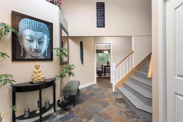 Foyer with slate tile flooring, a console table, and a staircase with wood railings. - 6173 Parkside Court, Surrey