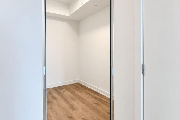 View through a glass sliding door into an empty room with white walls and wood floor. - 618 - 101 John Street N, Hamilton