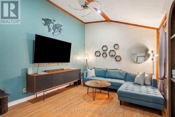 Living room with teal accent wall, large TV, and wooden furniture - 618 Lincoln Street, Welland