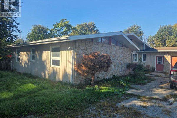 Side view of the house showing light-colored siding and stone walls. - 618 Mersea Road 8, Leamington