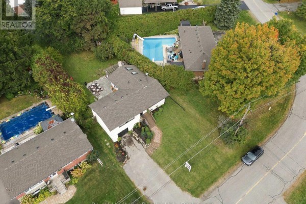 Aerial view of a residential street with houses, swimming pools, trees, and a paved road. - 618 Sunset Boulevard, Clarington