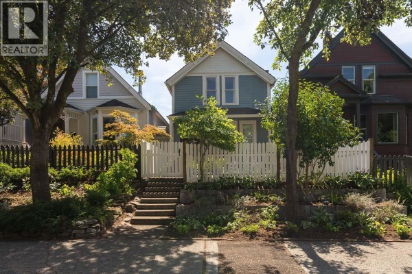 Close-up of the blue house exterior, showing the porch with seating and decorative trim. - 618 Union Street, Vancouver