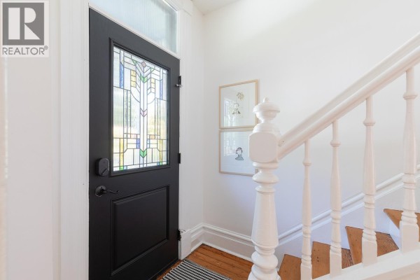 Interior view of the front entrance, featuring a black door with stained glass and a white staircase. - 618 Union Street, Vancouver