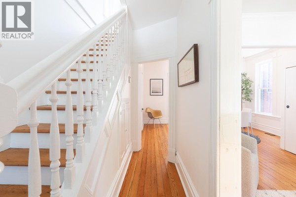 Hallway inside the house with a white banister, wooden floor, and a view into another room. - 618 Union Street, Vancouver