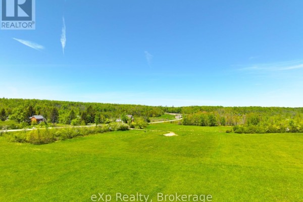 Wide aerial view of green fields, scattered houses, and a dense treeline on a sunny day. - 618129 Grey Road 18, Meaford