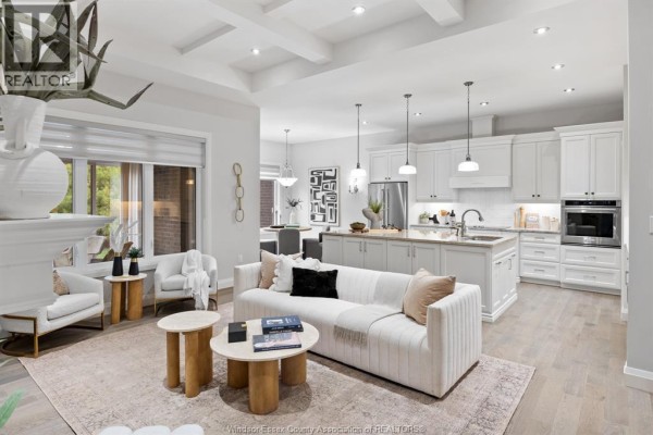 Open-concept living room and kitchen with white cabinetry, stainless steel appliances, and a large island. - 6185 Forest Trail Crescent, Lasalle