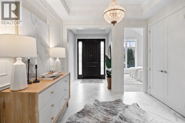 Front entryway with a dark wood door, marble tile floor, and a wooden dresser with lamps. - 6185 Forest Trail Crescent, Lasalle