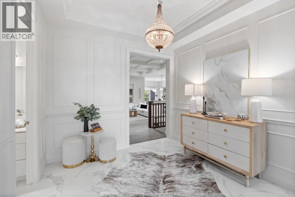 Interior view of a bright hallway with white wainscoting, marble floors, and a decorative chandelier. - 6185 Forest Trail Crescent, Lasalle