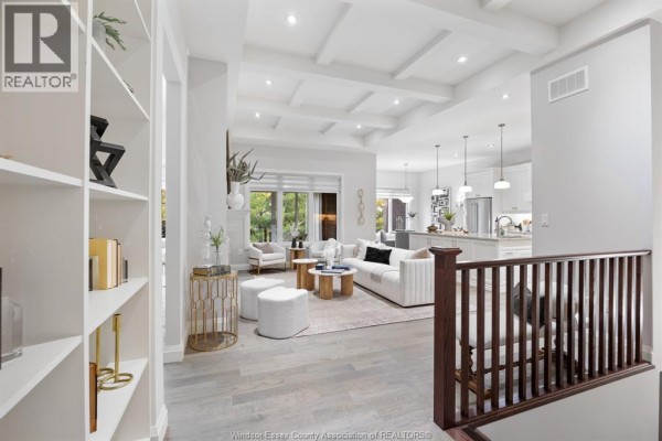 View of a living room with coffered ceilings, white furniture, and an adjacent kitchen area. - 6185 Forest Trail Crescent, Lasalle