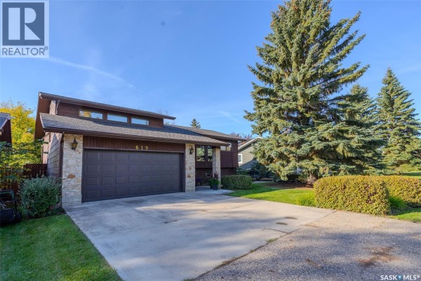 Side view of the house showing the double garage, stone and wood exterior, and large evergreen trees. - 619 Clover Avenue, Dalmeny