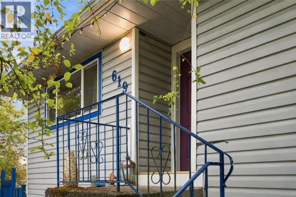 Close-up of the house entrance at 619 Pine St, showing grey siding, blue railings, and a purple door. - 619 Pine St, Nanaimo