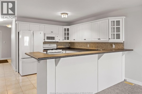 Empty bedroom with grey carpet, white walls, and a single window with a view of trees. - 619 Rodfam, Windsor