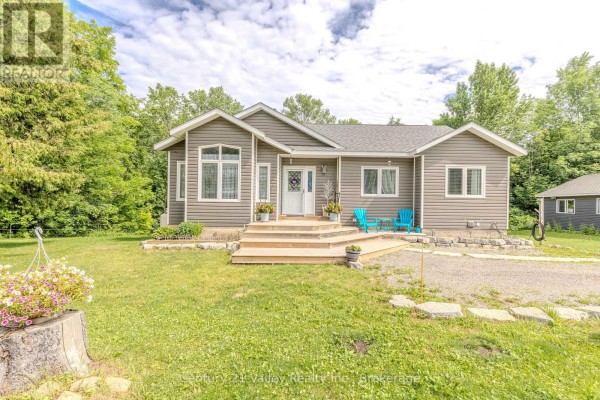 Aerial view shows the bungalow and garage with an above-ground pool, set against a backdrop of trees. - 6196 132 Highway, Bonnechere Valley