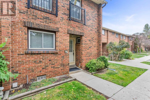 Close-up of a brick townhouse exterior with a front door and window. - 62 - 201 Silvercreek Parkway N, Guelph