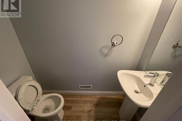 Powder room with a white toilet, pedestal sink, chrome faucet, and light grey walls. - 62 - 819 Kleinburg Drive, London North