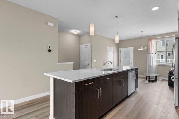Open kitchen layout with pendant lights, access to the entryway, and large windows - #62 13139 205 St Nw, Edmonton