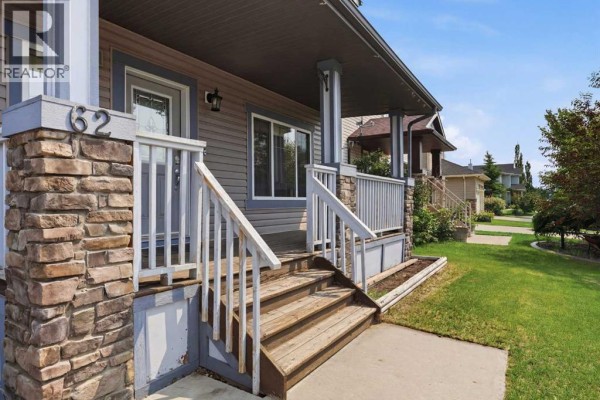 View of the front porch steps and railing with stone pillar accents and beige siding. - 62 Besse Avenue Nw, Langdon