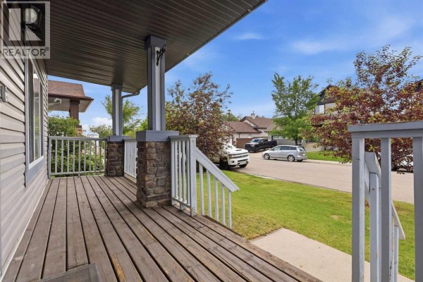 View of the covered wooden front porch with white railing and a street view. - 62 Besse Avenue Nw, Langdon