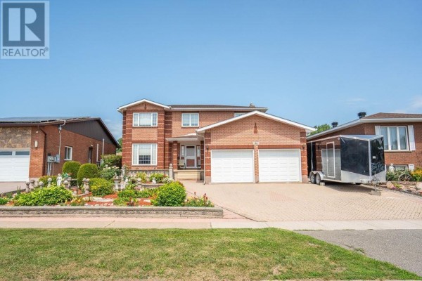 Front view of a red brick house with a double garage, paved driveway, and decorative landscaping. - 62 Bitonti Cres, Sault Ste  Marie