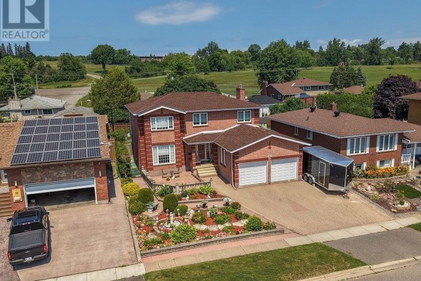 Aerial view of a large red brick house with a double garage, surrounded by neighboring homes and greenery. - 62 Bitonti Cres, Sault Ste  Marie