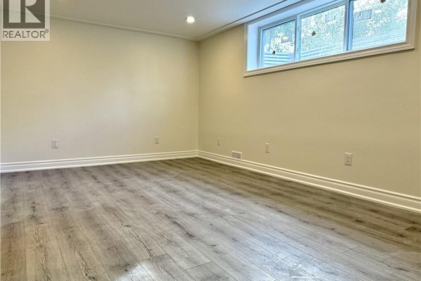 Empty room with light beige walls, gray wood-look laminate flooring, and a small window. - 62 Bond Street Unit# 1, Kitchener