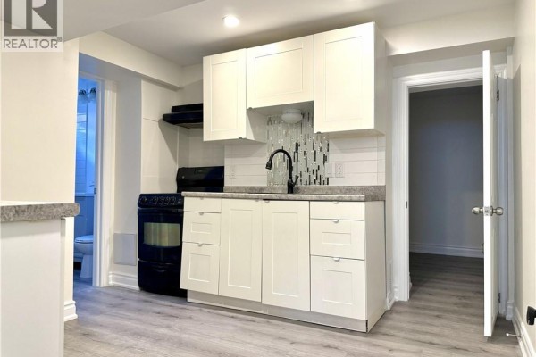 Compact kitchen with white cabinets, black appliances, gray countertops, and a glass tile backsplash. - 62 Bond Street Unit# 1, Kitchener