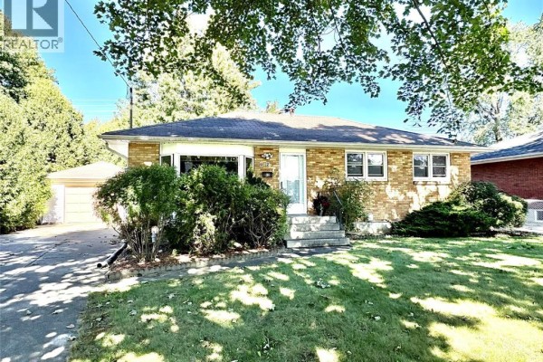 Exterior of a beige brick bungalow with a manicured lawn and mature trees. - 62 Burton Avenue, Chatham