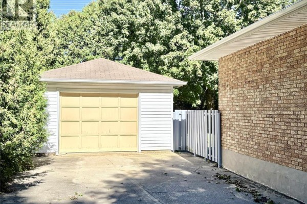 A single-car detached garage with a yellow door next to a brick house. - 62 Burton Avenue, Chatham