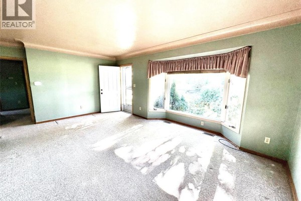 Living room with a large bay window, light green walls, and carpet flooring. - 62 Burton Avenue, Chatham