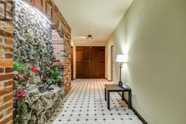 Hallway with white and black checkered tile flooring and a decorative brick and stone wall feature. - 62 Chapel Street, Brampton