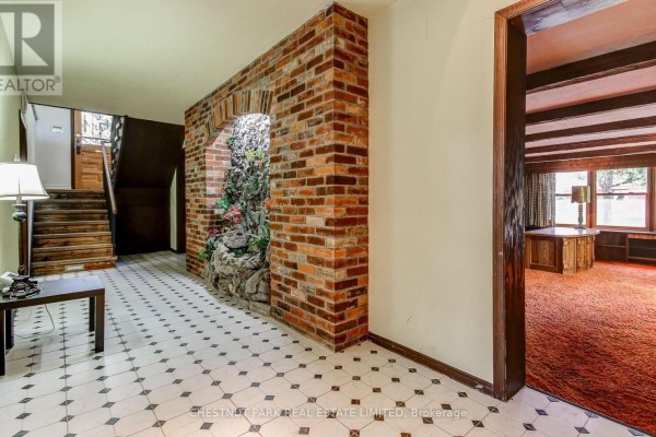 Hallway entrance with a view of a staircase and an adjacent room with wood paneling. - 62 Chapel Street, Brampton