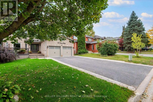 View of the front of a brick house with a large lawn and a paved driveway. - 62 Corner Ridge Road, Aurora