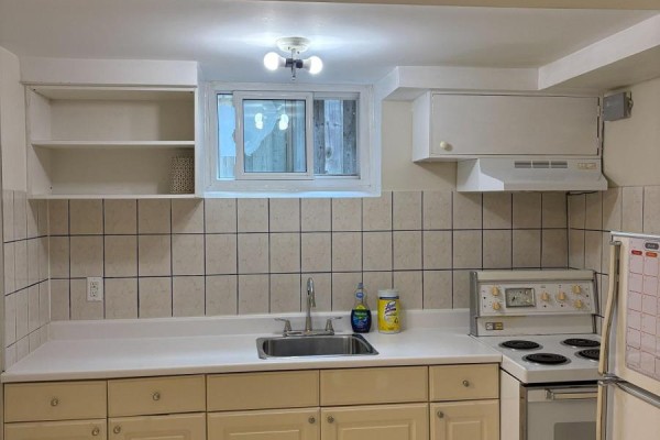 Room with built-in dark wood bookshelves, a white refrigerator, and light tan flooring. - Bsmt #1 - 62 Cresthaven Drive, Toronto