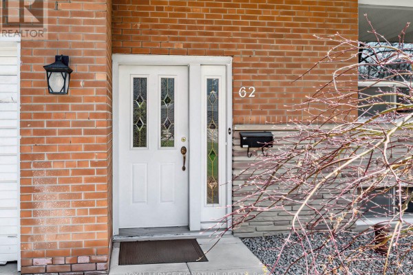 Living room with a large stone fireplace, hardwood floors, pastel green walls, and floral patterned furniture. - 62 Dukinfield Crescent, Toronto