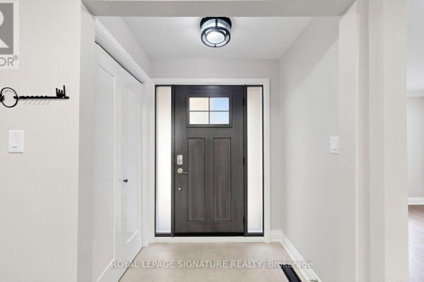 Interior view of a spacious entryway with a dark wood front door and beige tile flooring. - 62 Emeline Crescent, Markham