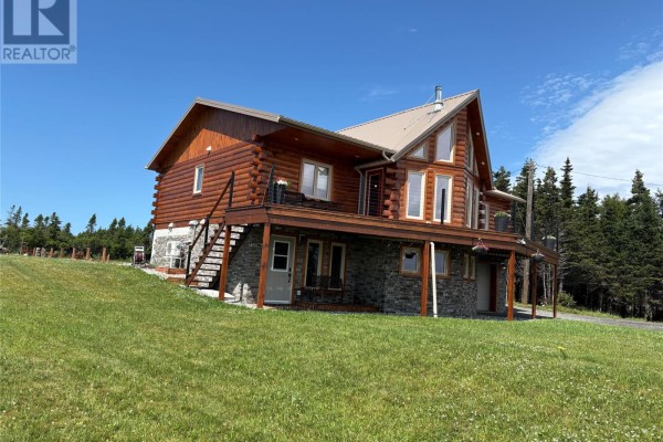 View of the ocean from the property, with a foreground of landscaping, green grass, trees, and power lines. - 62 Front Road, Port Au Port West