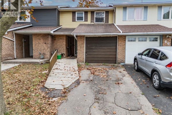 Close-up of townhouse front entrance with brick facade, wooden garage door, and ramp. - 62 Gledhill Crescent, Hamilton