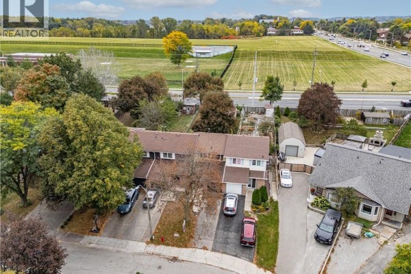 Aerial view of townhouses with surrounding neighborhood, street, and distant fields. - 62 Gledhill Crescent, Hamilton