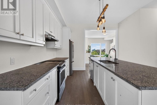 View of kitchen counter space with dark granite, white cabinets, and island sink. - 62 Hesperus Road, Vaughan