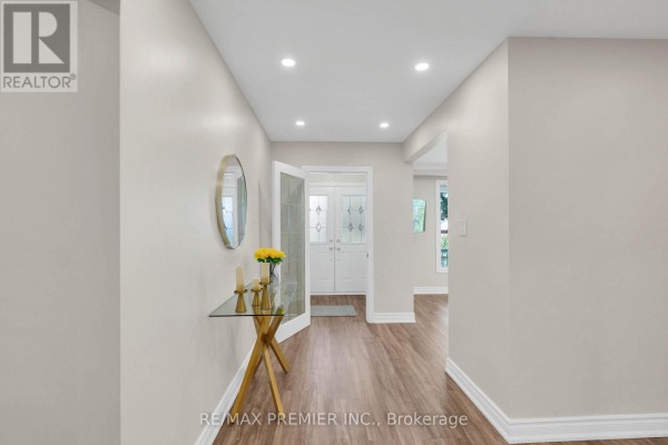 Interior hallway with beige walls, wood-look flooring, leading to double glass doors. - 62 Keegan Crescent, Toronto
