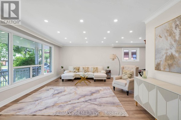 Living room with large windows, a sectional sofa, armchair, and a marble-patterned rug. - 62 Keegan Crescent, Toronto
