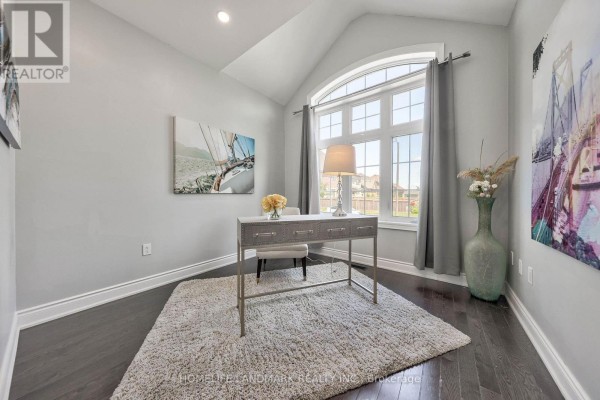 Home office with a desk, chair, arched window, and plush rug. - 62 Ladder Crescent, East Gwillimbury