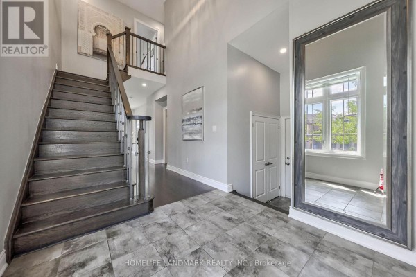 Foyer with dark wood staircase, gray tile floor, and large floor mirror. - 62 Ladder Crescent, East Gwillimbury