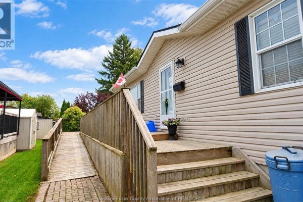 Wooden ramp leading to the front porch of the modular home with beige siding. - 62 Malden Hill Drive, Amherstburg