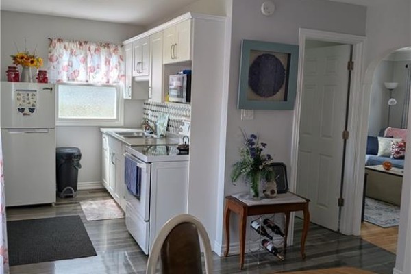 Kitchen with white cabinets, stove, fridge, and wood-look flooring - 62 Ninth Avenue Brantford