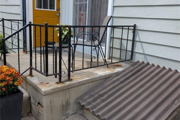 Yellow door and porch with metal railing - 62 Ninth Avenue Brantford