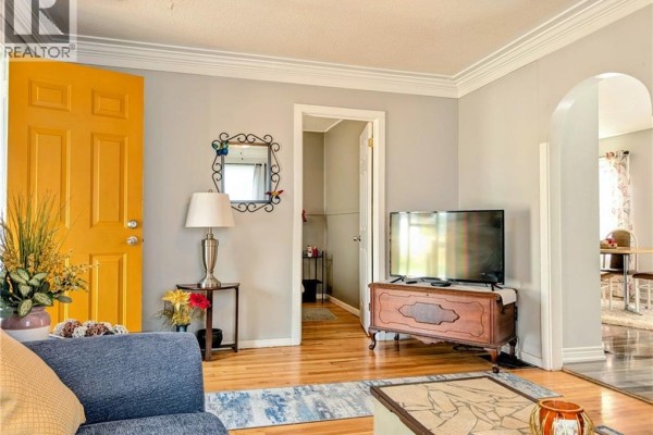 Living room with blue sofa, brown recliner, wooden floor, ceiling fan, and a grandfather clock. - 62 Ninth Avenue, Brantford
