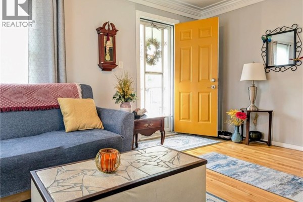 Living room with light grey walls, archway to dining area, TV on a chest, and wooden floor. - 62 Ninth Avenue, Brantford